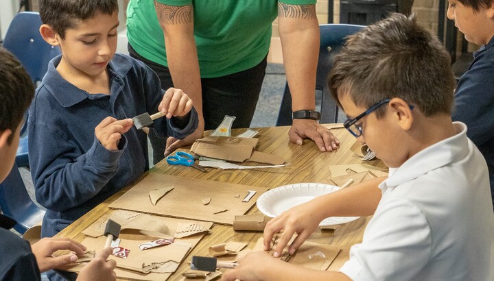Children in an after-school program get help from an educator with an art project.