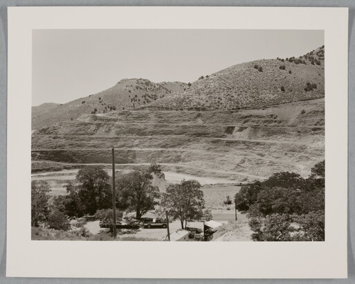 A black-and-white photograph of a mountainside that has been strip mined and the town below.