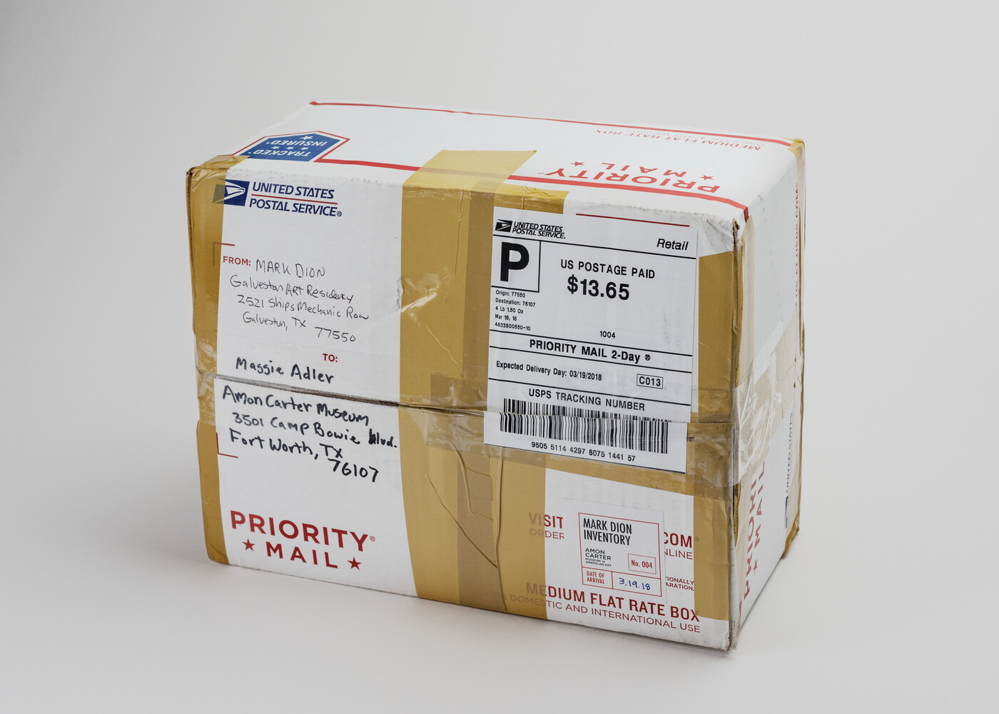 A USPS Priority Mail box covered in packing tape and a postage sticker addressed to the Carter.