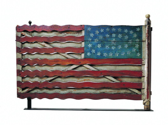 A wood gate painted to look like an American flag with wavy red stripes.