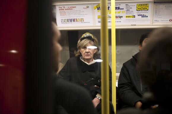 A color photograph looking through the window of a subway train of people seated.
