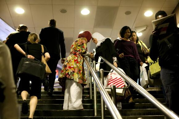 A color photograph of interior steps bisected by the handrail: on the left people go up the steps, and on the right they go down.