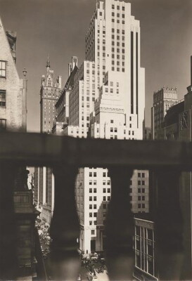 A black-and-white photograph of a white skyscraper bisected by a concrete railing which partially obscures the bottom half of the building.
