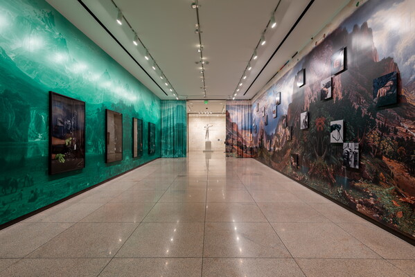A photo of a Carter gallery with four large framed photographs on a green-tinted landscape on the left, and a large reproduction of an Albert Bierstadt print on the right.