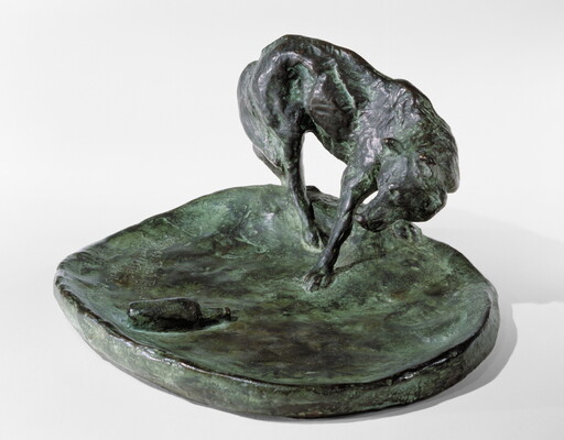 A bronze sculpture of a wolf staring at a bottle on the ground.