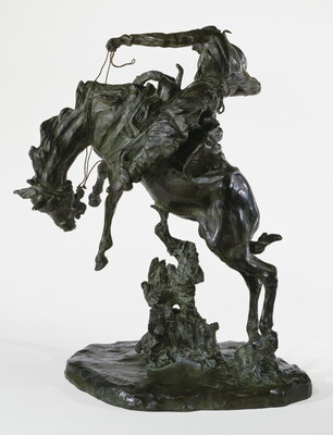 A bronze sculpture of a cowboy on horseback holding the reins as the horse raises up on its hind legs.