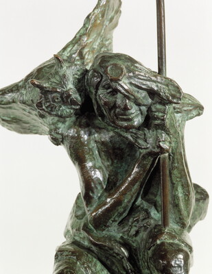A detail bronze sculpture of a crouching Indigenous person holding a spear with a open-winged bird perched on their shoulder.