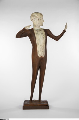 A wood sculpture of a male orchestra conductor standing with his arms raised out to his side.
