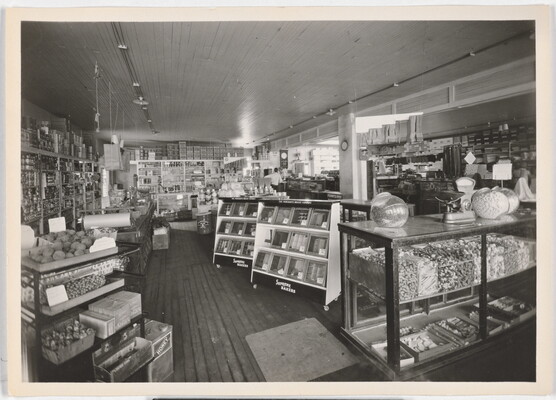 A black-and-white photograph of the interior of a grocery store from the early 20th century.