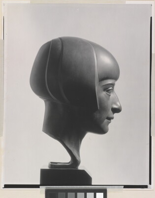 A black-and-white photograph of a bronze bust of a woman in profile with a bobbed haircut.