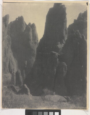 A black-and-white photograph of large hoodoos, or vertical spires of rock.