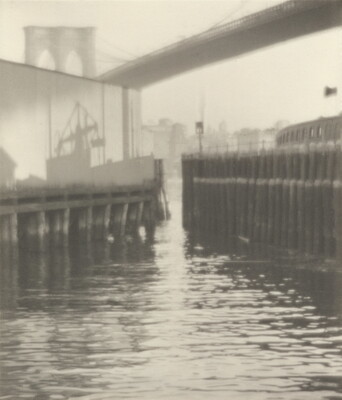 A black-and-white photograph of the shadow of a ship on top of a pier in a busy harbor.
