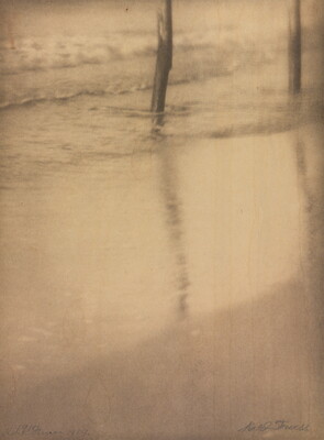 A sepia-toned photograph of water washing on a sandy beach around two poles in the top left corner.
