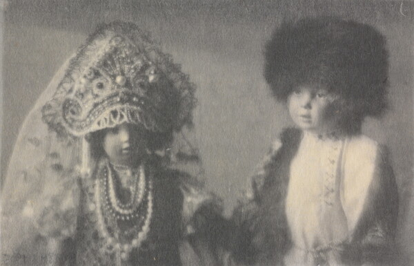 A black-and-white photograph of two light-colored dolls wearing Russian imperial clothing.
