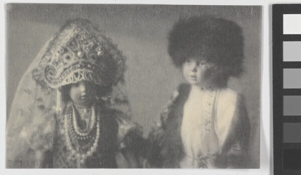 A black-and-white photograph of two light-colored dolls wearing Russian imperial clothing.