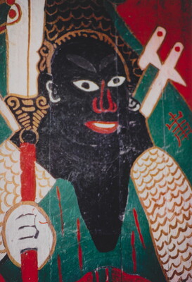 A color photograph of a mural featuring an abstract figure with curly hair and black skin, holding a decorative scepter.