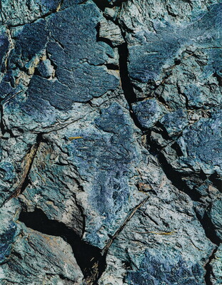 A color close-up photograph of a rough blue-tinged rock with cracks.