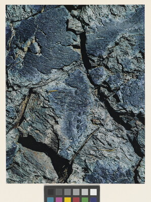 A color close-up photograph of a rough blue-tinged rock with cracks.