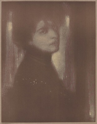 A dark, soft-focus black-and-white portrait photograph of a White woman with her hair up and head turned over her shoulder to face the camera.