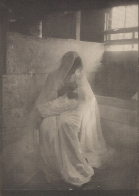 A soft-focus, black-and-white photograph of a seated woman wearing a white dress and veil, holding a baby wrapped in a white blanket.