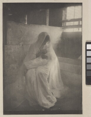 A soft-focus, black-and-white photograph of a seated woman wearing a white dress and veil, holding a baby wrapped in a white blanket.