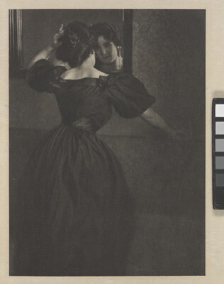 A black-and-white photograph of a young White woman, back to the camera, wearing a long, black dress with puffy sleeves fixing her hair in a mirror.