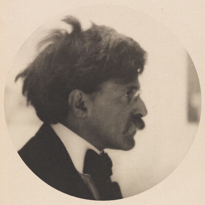 A circular black-and-white photograph of a White man in profile, disheveled hair, glasses, mustache, wearing a jacket with a bowtie.