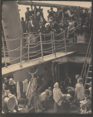A black-and-white photograph of people outside on two decks of a crowded ship.