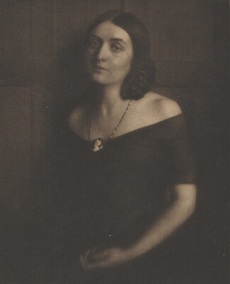 A sepia-toned portrait photograph of a young White woman wearing an off-the-shoulder dress and a cameo necklace.