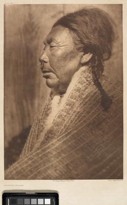 A sepia-toned photograph of an older Indigenous woman in profile with her hair in a braid, a ring through the septum of her nose, and a shawl around her shoulders.