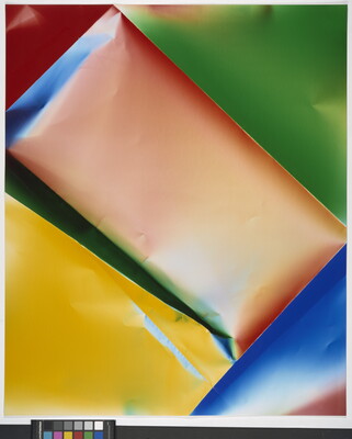 A color photograph of what looks like crinkled paper of orange and yellow rectangles surrounded by a blue, green, and red triangles.