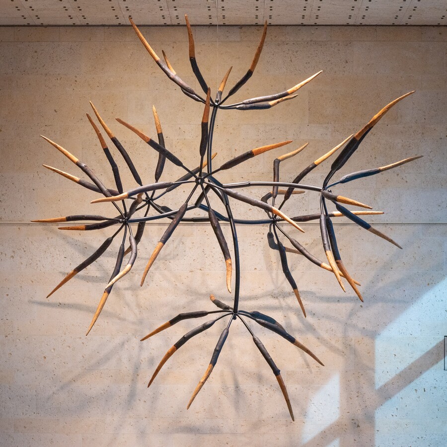 A large direct-carve wooden sculpture with seven parts suspended from the ceiling