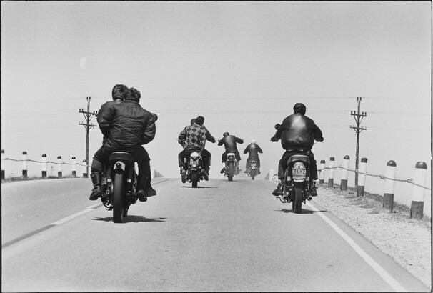 A road with five motorcyclists driving away