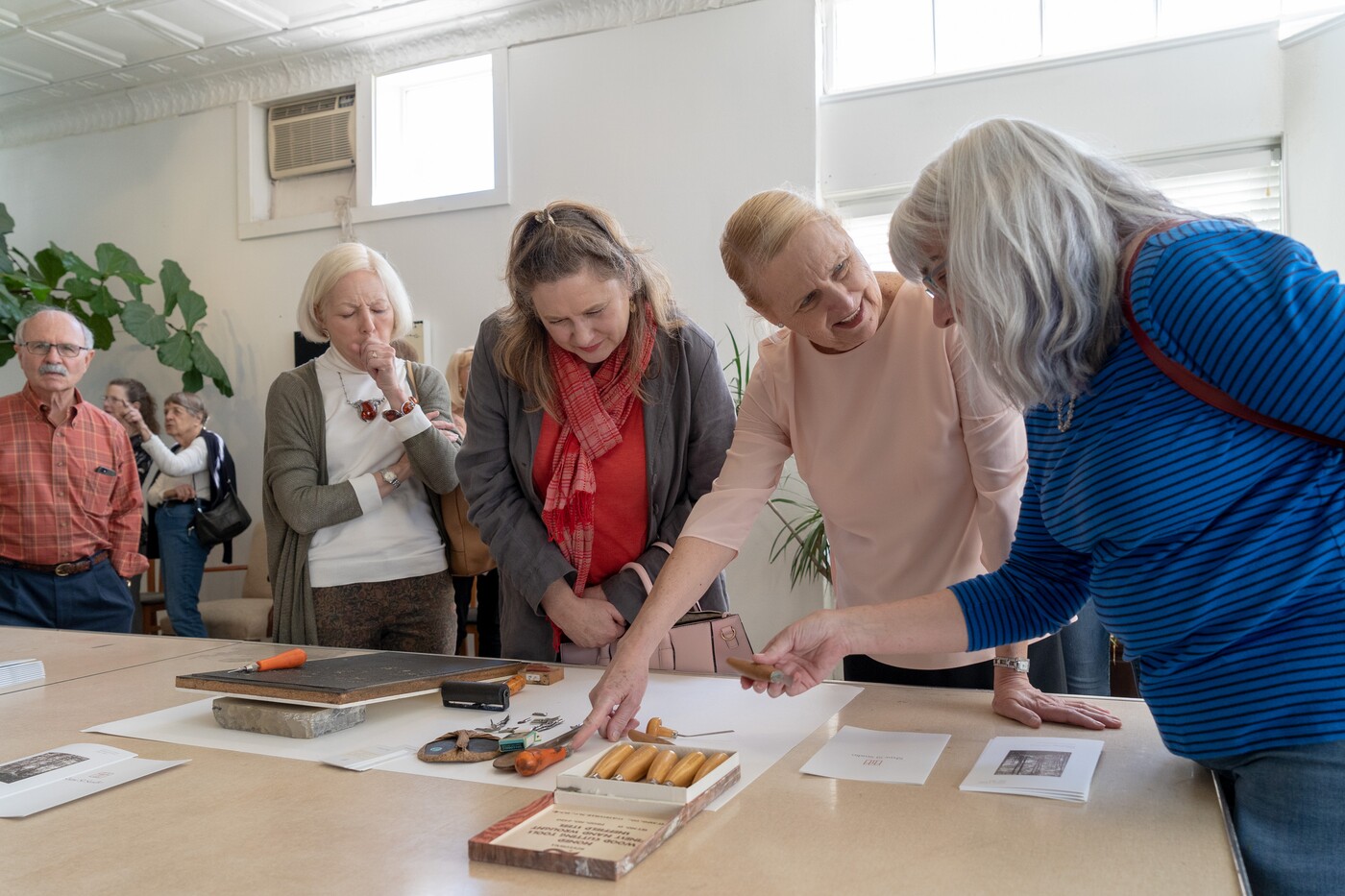 group of women examining art objects on a table