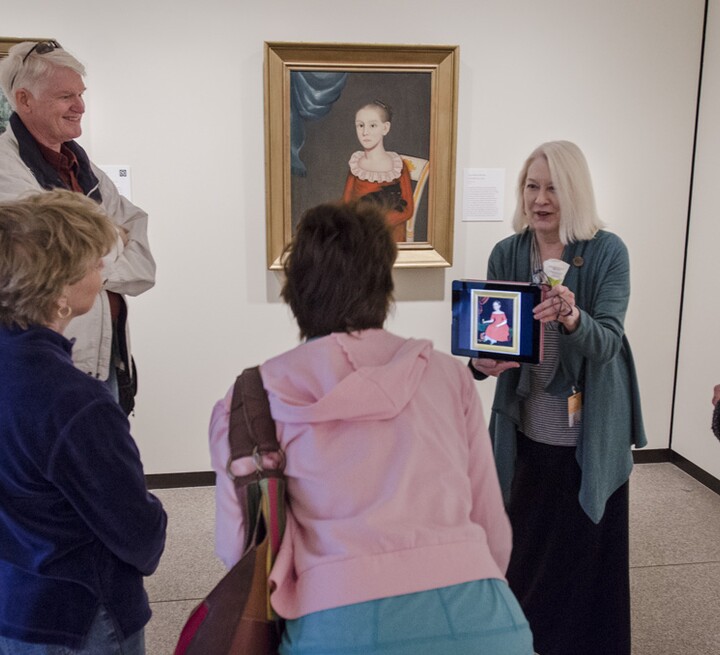 Docent shows iPad and painting to group