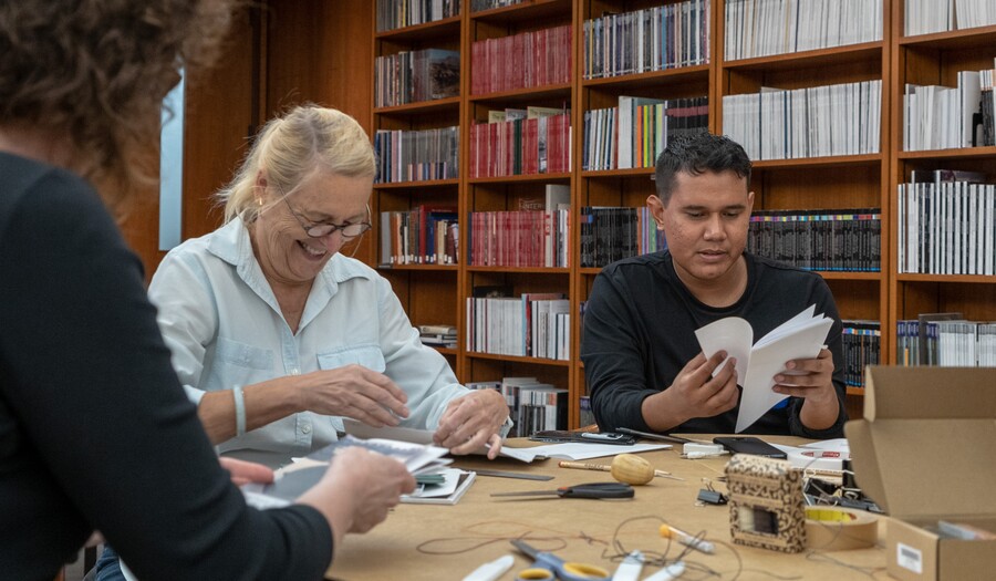 A woman and man sit at a table making a photo book