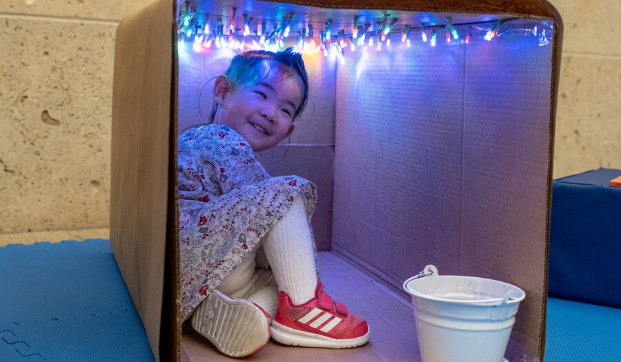toddler playing in a cardboard box with lights