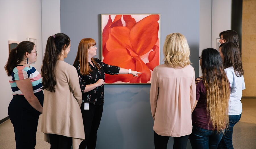 group of women on a tour in an art museum in front of a painting with a flower