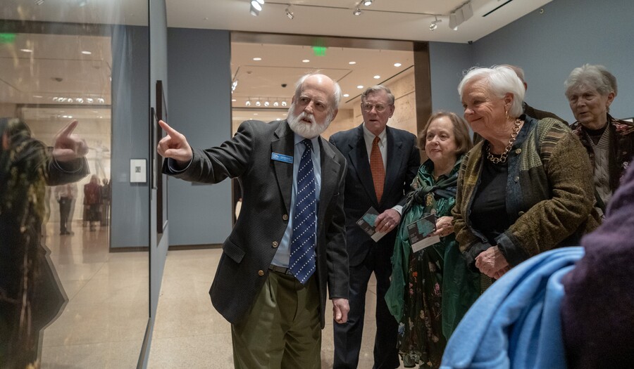group of people on a tour with a curator in front of a photo