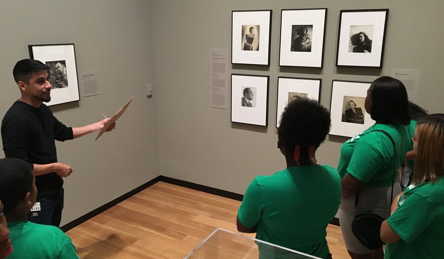 A group of teenagers and a guide stand in front of Gordon Parks photographs