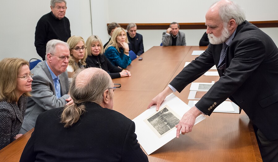 Man holds photograph up to show seated group