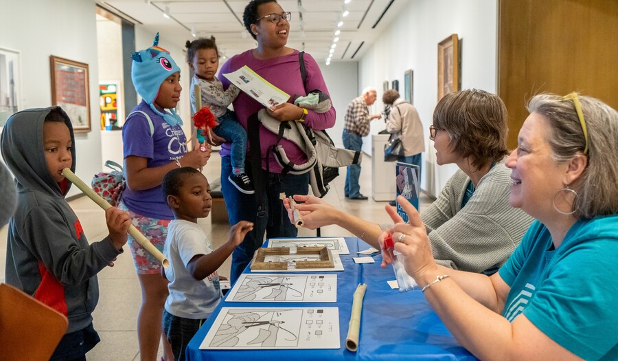 Children and adults in gallery around table with interactive activities