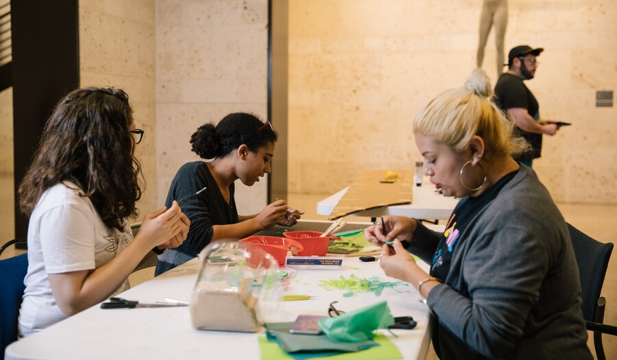 three women crafting in front of a statue