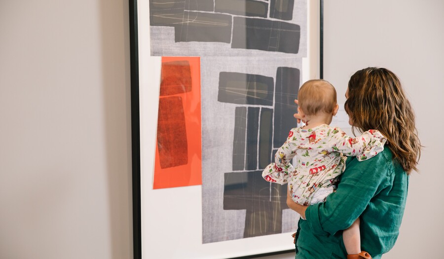mom and baby looking at a work on paper with black and white and red blocks