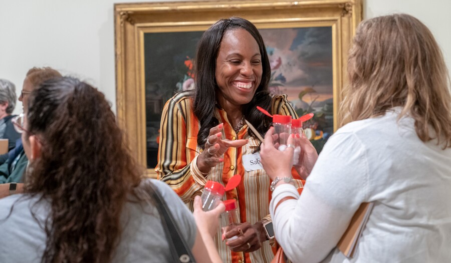 Women standing in gallery smell from clear open bottles