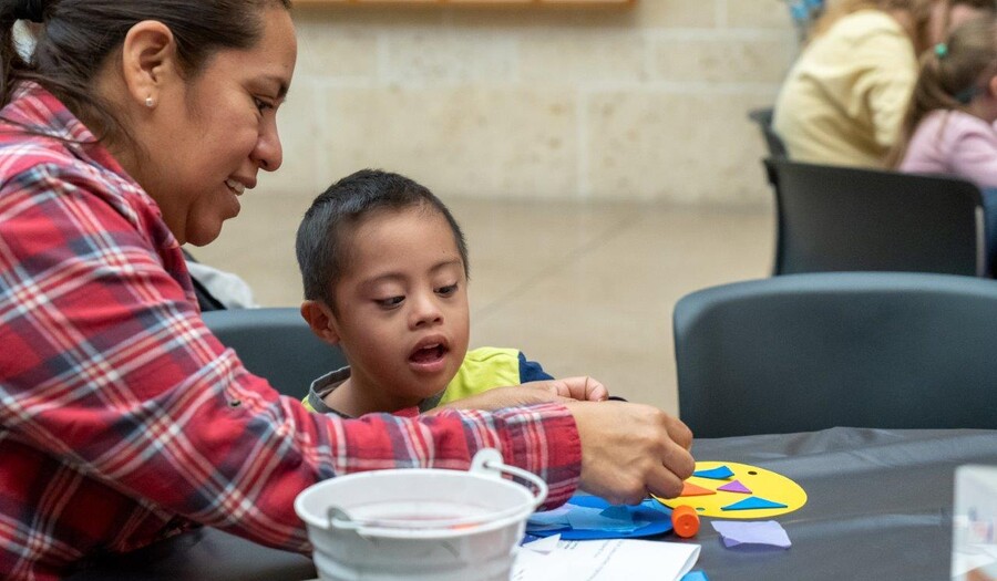 A woman helps a little child with an art project