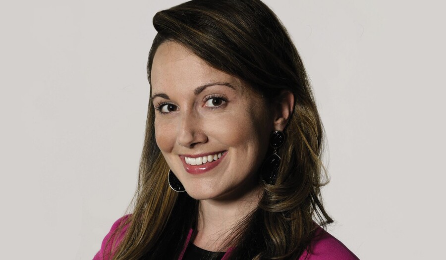 Headshot of a smiling woman with long dark brown hair and blue eyes.