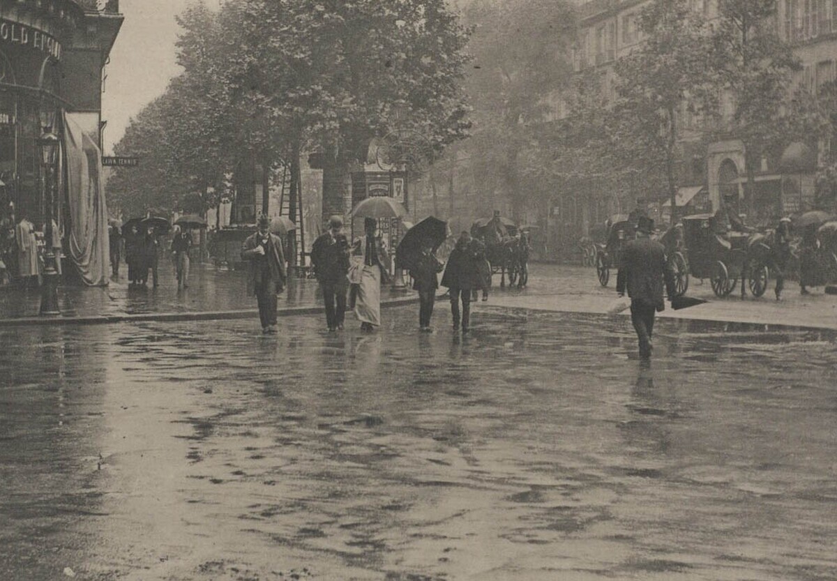 Photo from the 1920s of people walking along a wet street in Paris